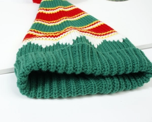 Detailed knit texture of colorful striped Christmas hat with red pompom and thick brim
