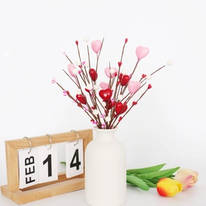 Détail de tiges de baies en forme de cœur rose et rouge dans un vase en céramique