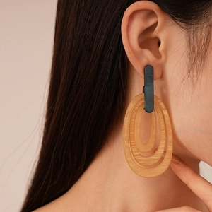 Close-up of amber resin striped oval geometric earrings worn by a female model