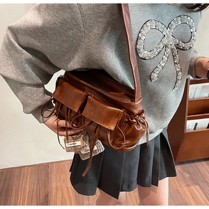 Close-up of vintage brown high-shine leather shoulder bag with multi-pocket bow design