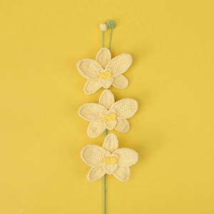 Detailed close-up of three handcrafted yellow crochet orchid flowers with green stems