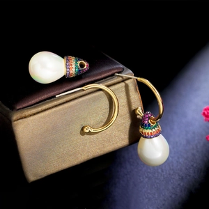 Macro detail of gold teardrop pearl earrings with colorful zircon stones and C-shaped hooks