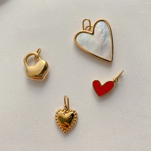 Detailed macro view of heart pendants featuring white shell, red enamel, and gold textures
