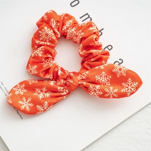 Detail of orange Christmas scrunchie with white snowflake print and bunny ear bow