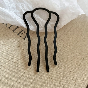Détail d'un peigne à cheveux noir à 4 dents avec dents ondulées pour chignon