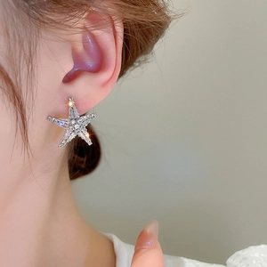 Close-up of star-shaped earrings with clear zircons worn by model for elegant style
