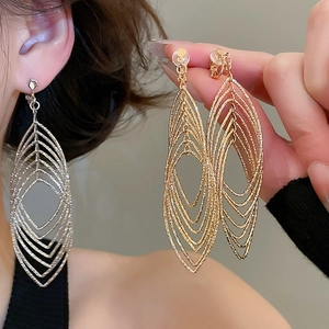 Close-up of gold and silver multilayer hollow leaf clip-on earrings with metallic texture