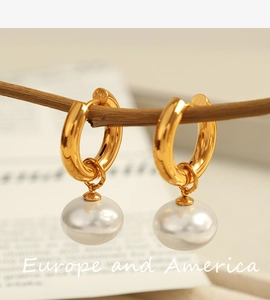 Macro view of gold hoop earrings with white pearls hanging on a wooden branch