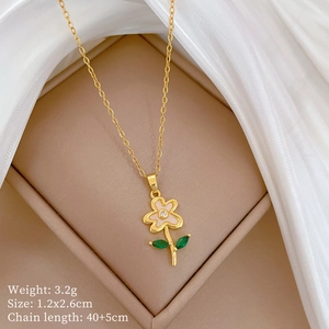 Macro shot of gold floral necklace with pink petals and green leaf in jewelry box