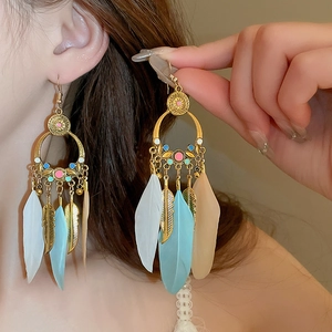 Detailed view of Bohemian gold hoop earrings with white, blue, and khaki real feathers