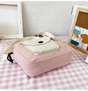 Detailed view of a pink canvas bucket bag with beige pocket and snap button closure