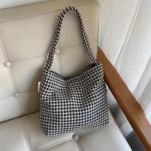 Detail of knitted tote bag with black and white houndstooth pattern and logo label