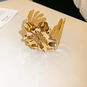 Detailed top view of a bold golden 3D flower cuff bracelet with layered petal texture