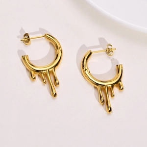 Close-up of golden irregular lava drop earrings with polished molten fluid metal design
