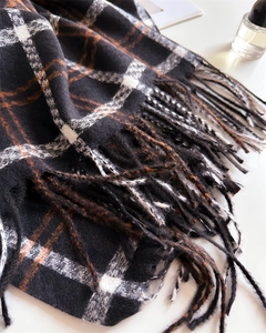 Detailed view of the soft plaid scarf texture with black, white, and brown tassel fringes