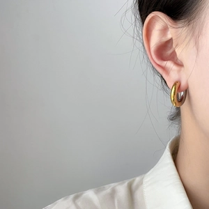 Detail shot of a two-tone curved hoop earring in polished gold and silver steel