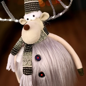 Detail of Christmas reindeer doll with grey plush body, green knit hat and scarf