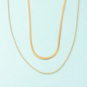 Double layered gold snake chain necklace with flat blade design on light blue background