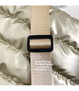 Detail of adjustable nylon strap and quilted satin fabric texture on tote bag