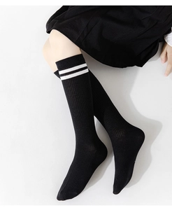 Detail of black knee-high cotton socks with white stripes and breathable mesh texture
