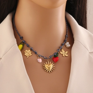 Détail d'un collier tressé coloré avec pendentifs soleil doré, cœur et papillon