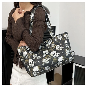 Detail view of large tote bag with gothic skull and floral print on a side-worn model