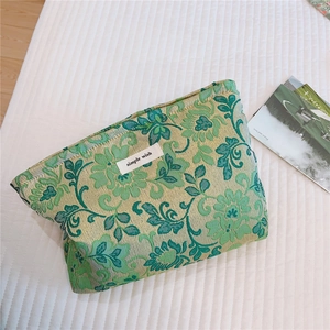 Detailed view of green floral jacquard fabric and simple wish woven label on the pouch
