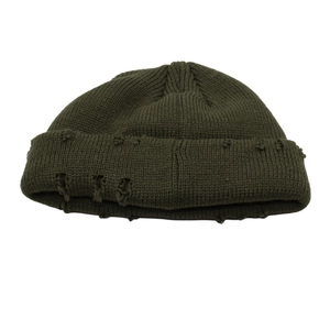Dettaglio del berretto in maglia verde scuro con fori usurati vintage e risvolto a coste