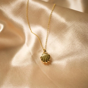 Vintage gold shell locket necklace with faux pearl on champagne silk background