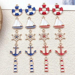Flat lay of 20 nautical enamel charms with anchors and ships on a beige background