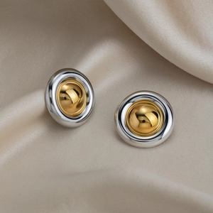 Vue détaillée des boucles d'oreilles bicolores or et argent sur un tissu en soie élégant
