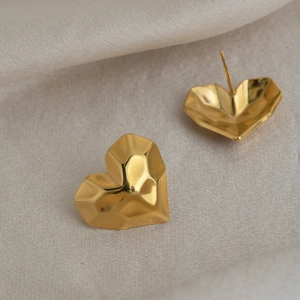 Macro detail of 18K gold-plated heart stud earrings with geometric faceted design