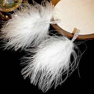 Elegant white feather tassel earrings with sparkling zircon studs on a black background