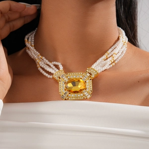Close-up of multilayer pearl necklace featuring a large yellow gemstone and gold inlay