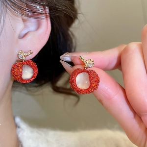 Detailed view of sweet zircon resin apple earrings worn on ear and held by hand.