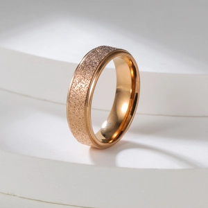 Detailed close-up of 2mm gold frosted stainless steel ring on a white pedestal