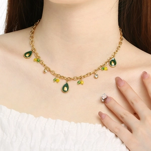 Golden chain necklace with avocado and cherry pendants on a model with white background