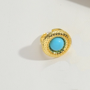 Detail view of gold textured ring featuring a round blue turquoise stone on white background