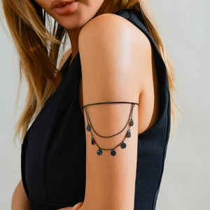Close-up of black gothic multi-layered armlet with chain tassels and round metal pendants