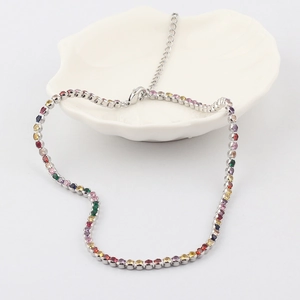 Rainbow cubic zirconia claw chain necklace with colorful stones in a white shell dish