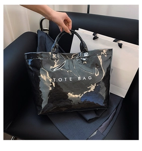 Glossy black Tyvek tote bag with white lettering on a luxury chair setup
