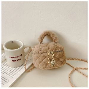Detailed view of brown plush quilted handbag with gold chain and camellia charm