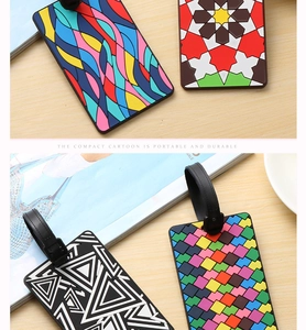 Detail of four stylish geometric luggage tags with adjustable black straps on a wood desk