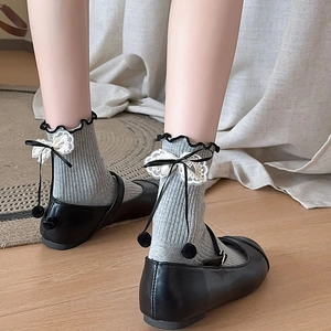 Detail of grey ribbed socks featuring black ruffle trim and delicate white lace bow accents