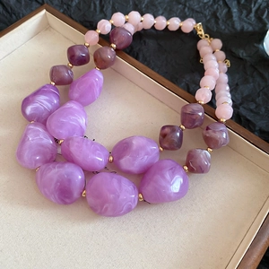 Close-up of double-layer purple acrylic beaded necklace with gold spacers on a tray