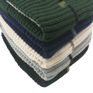 Detailed stack of thick ribbed knit beanies in green navy cream and grey colors