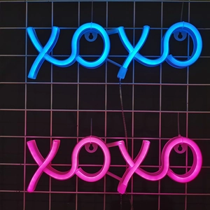 Pink and blue XOXO neon signs wall-mounted on white grid for festive home decoration