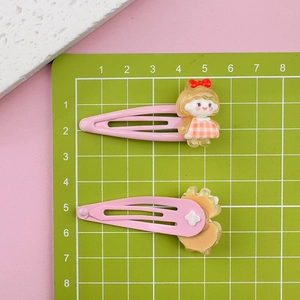 Close-up of pink cartoon girl hair clips on a measuring mat showing 5cm size scale