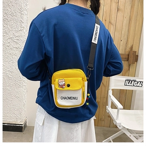 Detail of yellow and white canvas crossbody bag with adjustable strap and brand tag