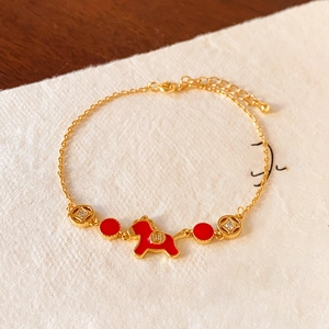 Detail of 18k gold plated pony pendant bracelet with red enamel and coin accents